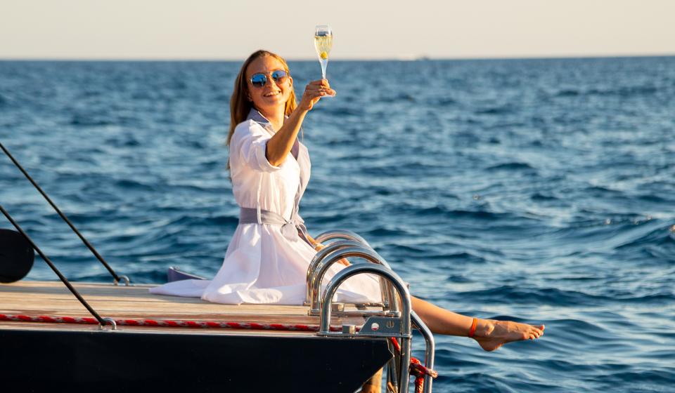 Woman drinking champagne on swim deck Oyster yacht Ibiza