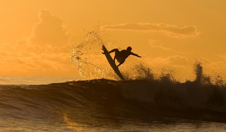 69. Man surfing big wave at sunset