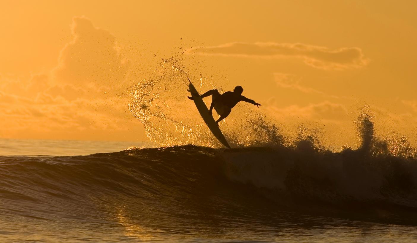 69. Man surfing big wave at sunset